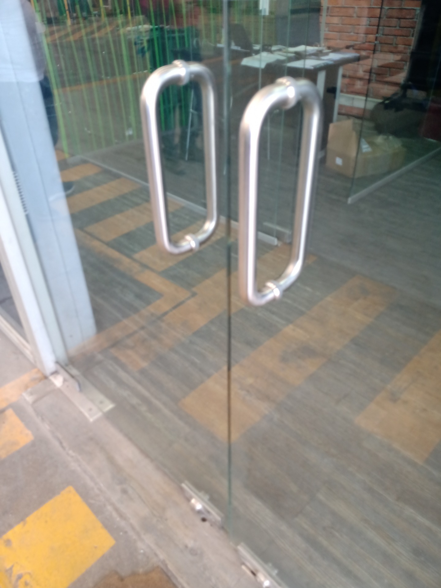Puerta en cristal de 10mm templado, con quicio hidráulico y tiradores en acero inoxidable